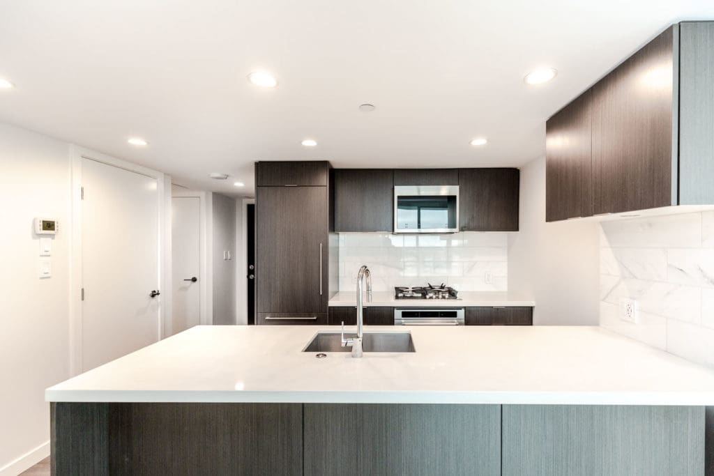 Kitchen with stainless steel appliances and white countertops in Vancouver luxury rental condo.