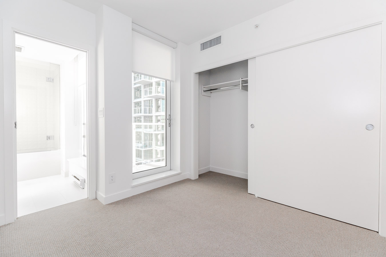 condo bedroom with window and closet with sliding doors