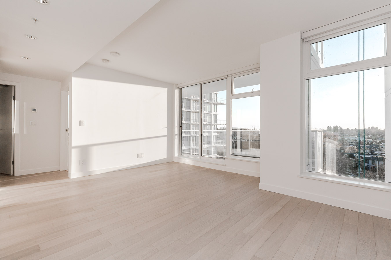 empty living room with white walls and hardwood floors and windows