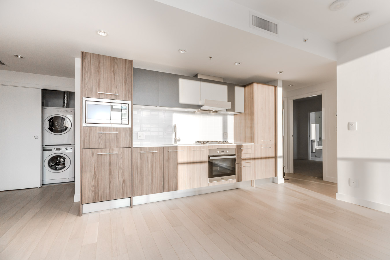 kitchen along the wall with wooden cabinets and hardwood floors in rental condo