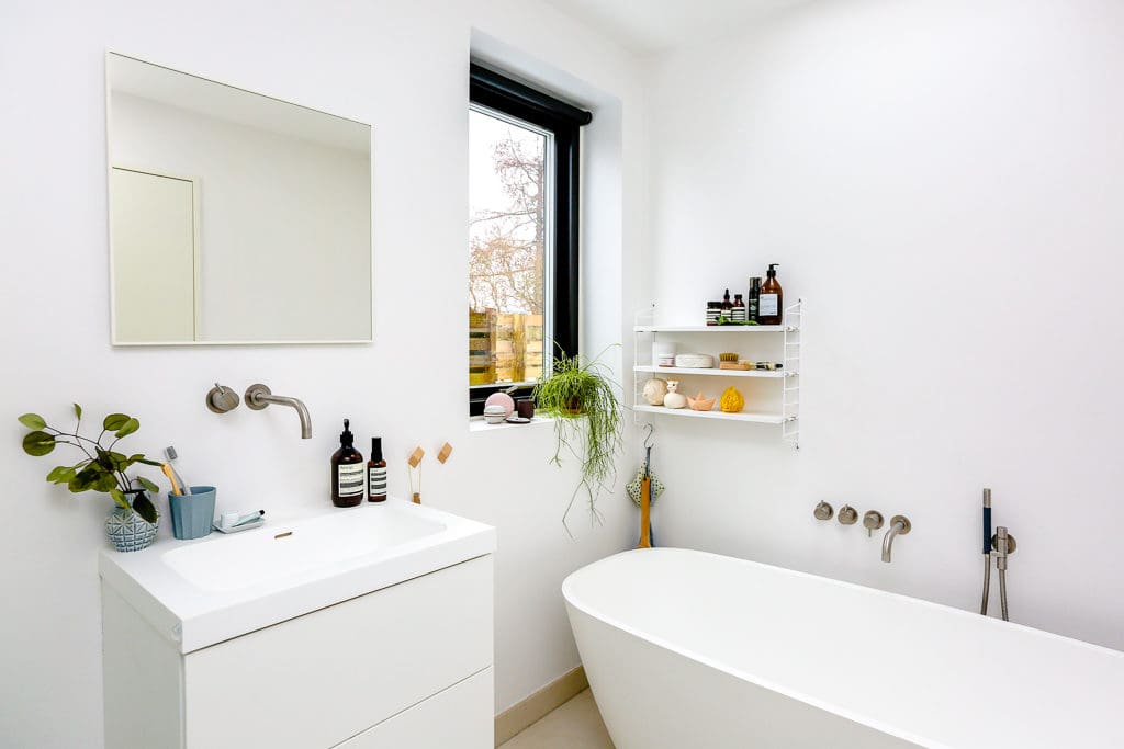 White bathroom featuring large tub and Aesop products