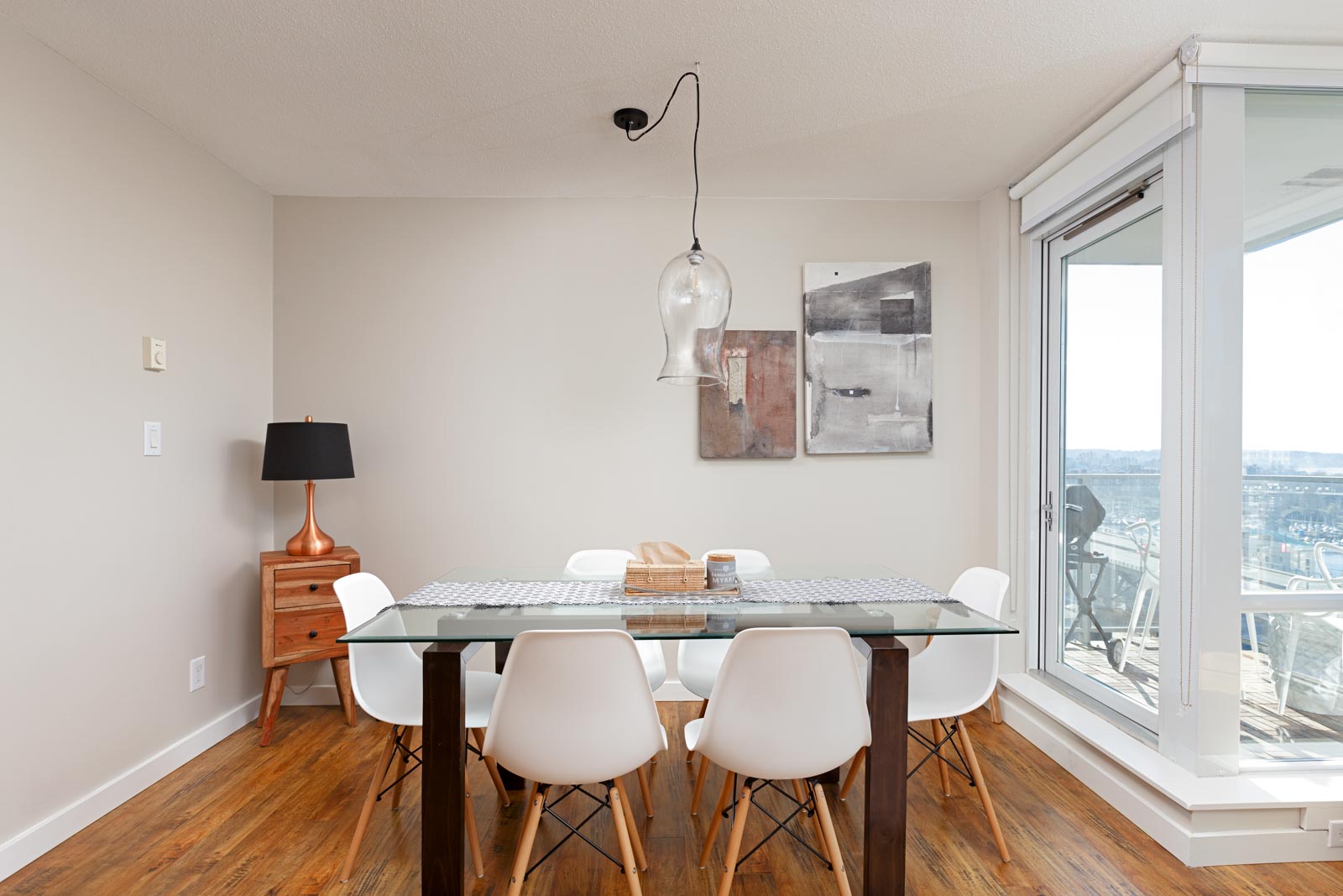 Dining area with glass top table and white chairs in Yaletown Vancouver condo with view.