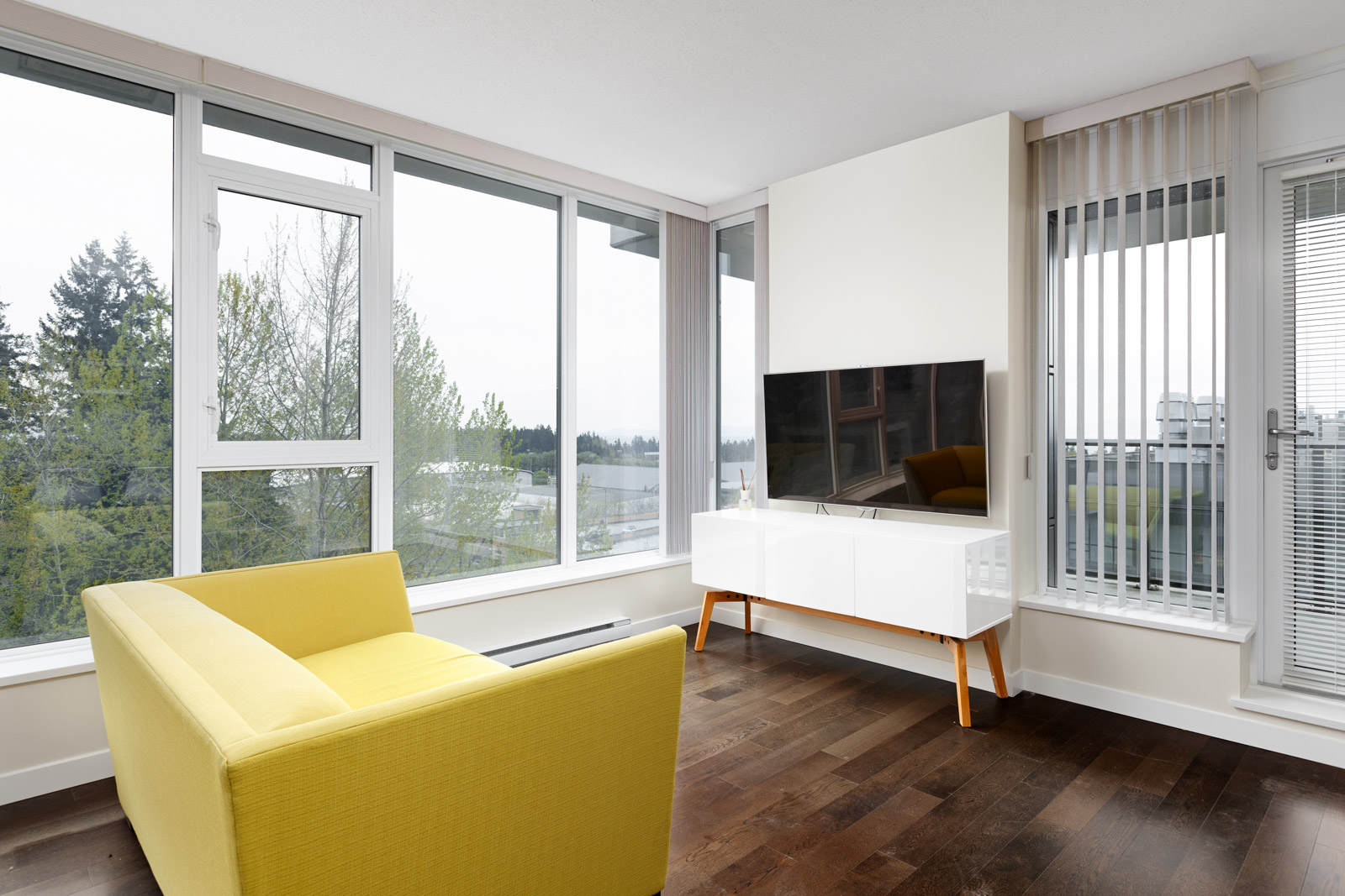 Living area featuring tv and yellow couch with view in UBC rental condo in Vancouver.