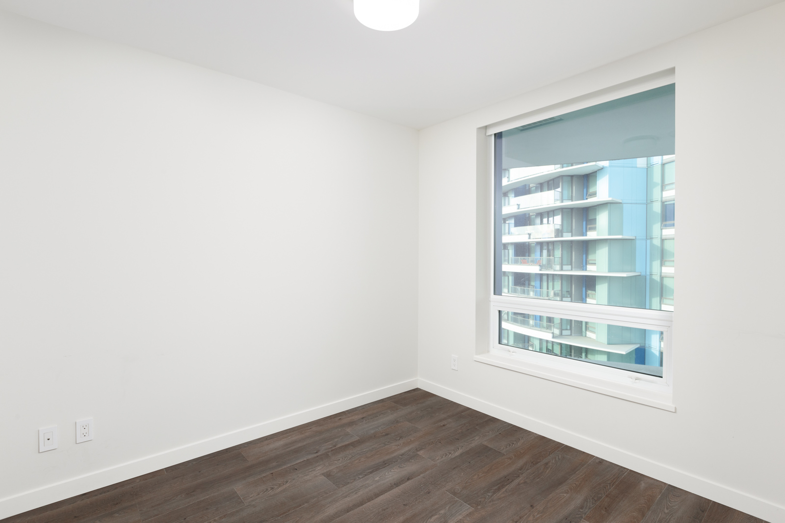 Bedroom with dark hardwood flooring inside luxury Downtown Vancouver condo.
