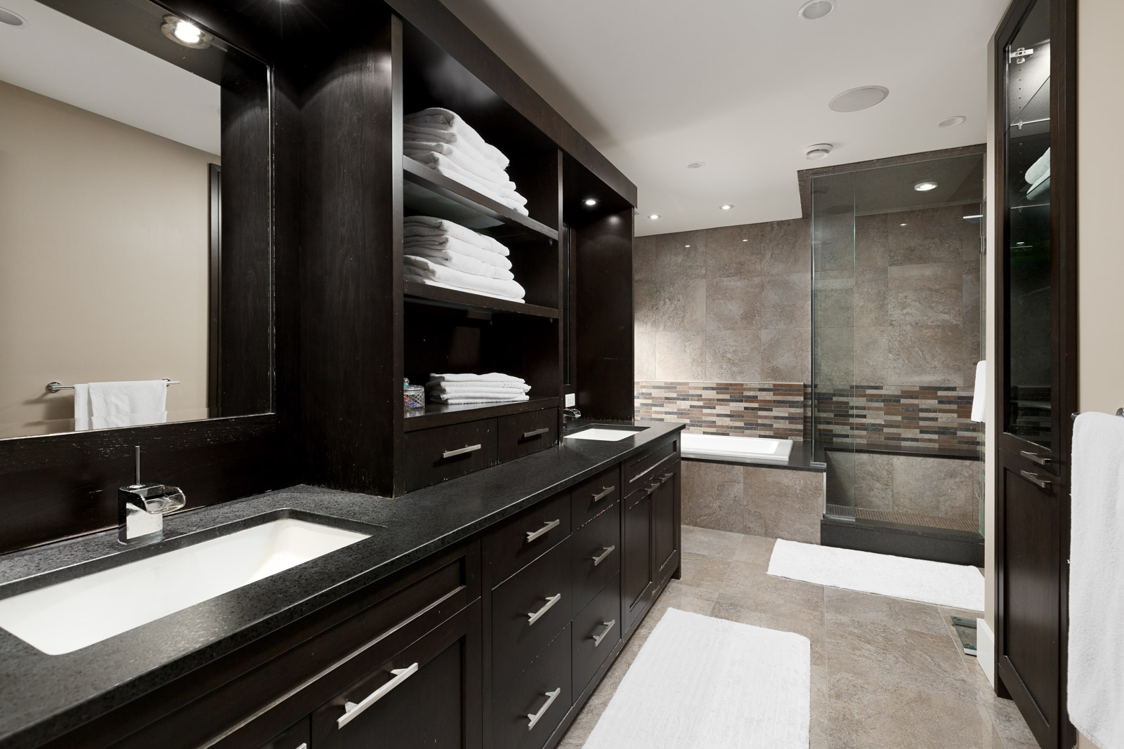 Bathroom with dark wood cabinetry and black counter tops inside North Vancouver luxury rental.