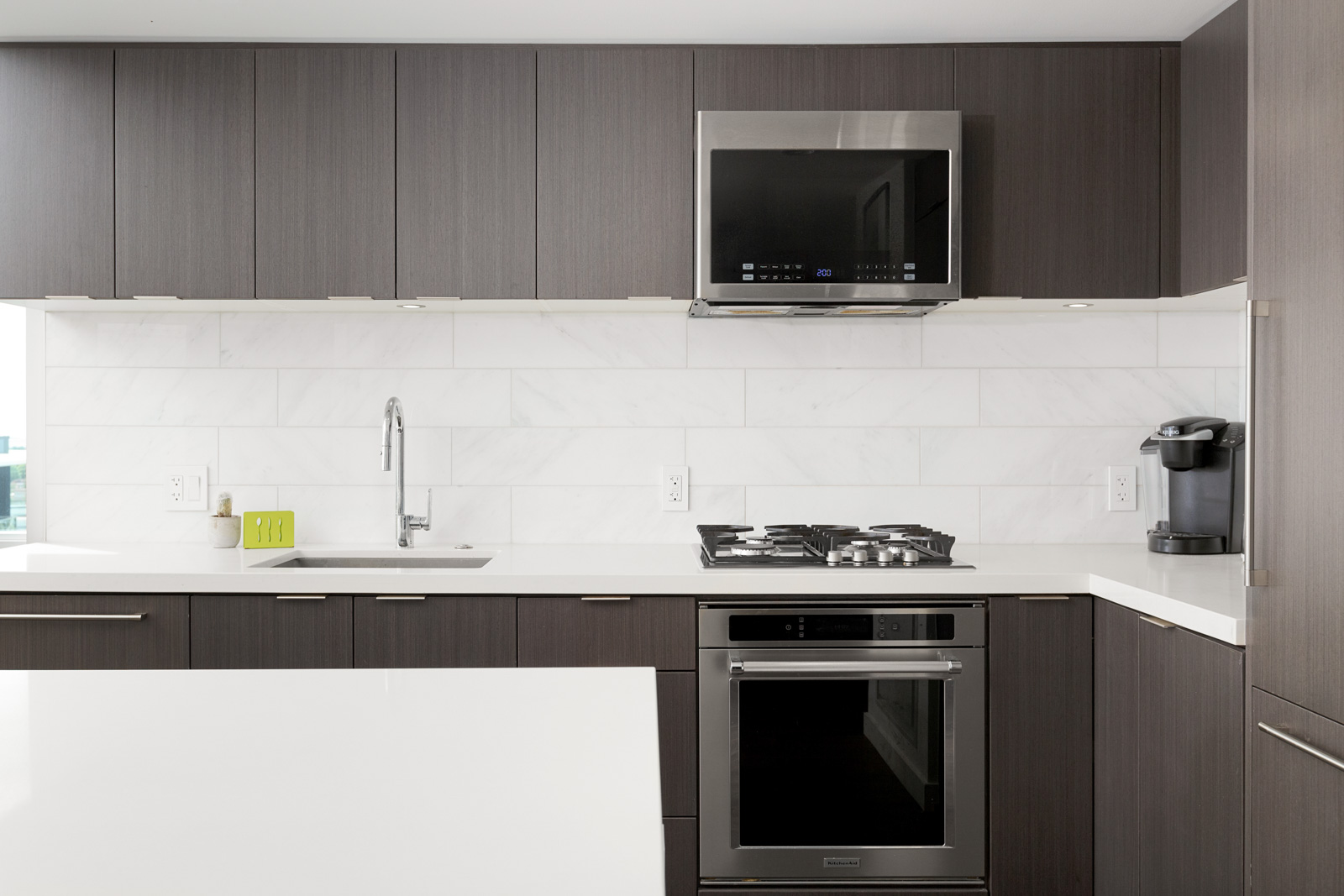 Kitchen with dark wood cabinetry and white counter top inside Vancouver luxury rental.