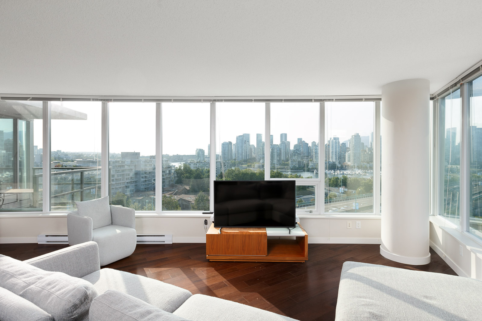 White couches surrounding a television overlooking the Vancouver city skyline.