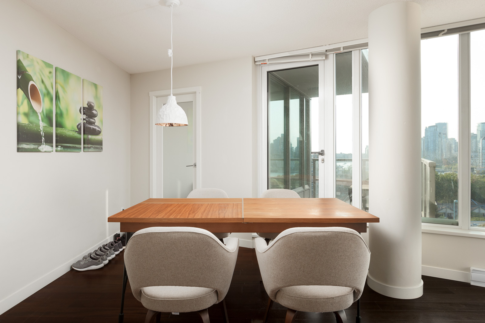 Rectangular wood table with four white upholstered chairs and a single hanging light inside Vancouver luxury rental.