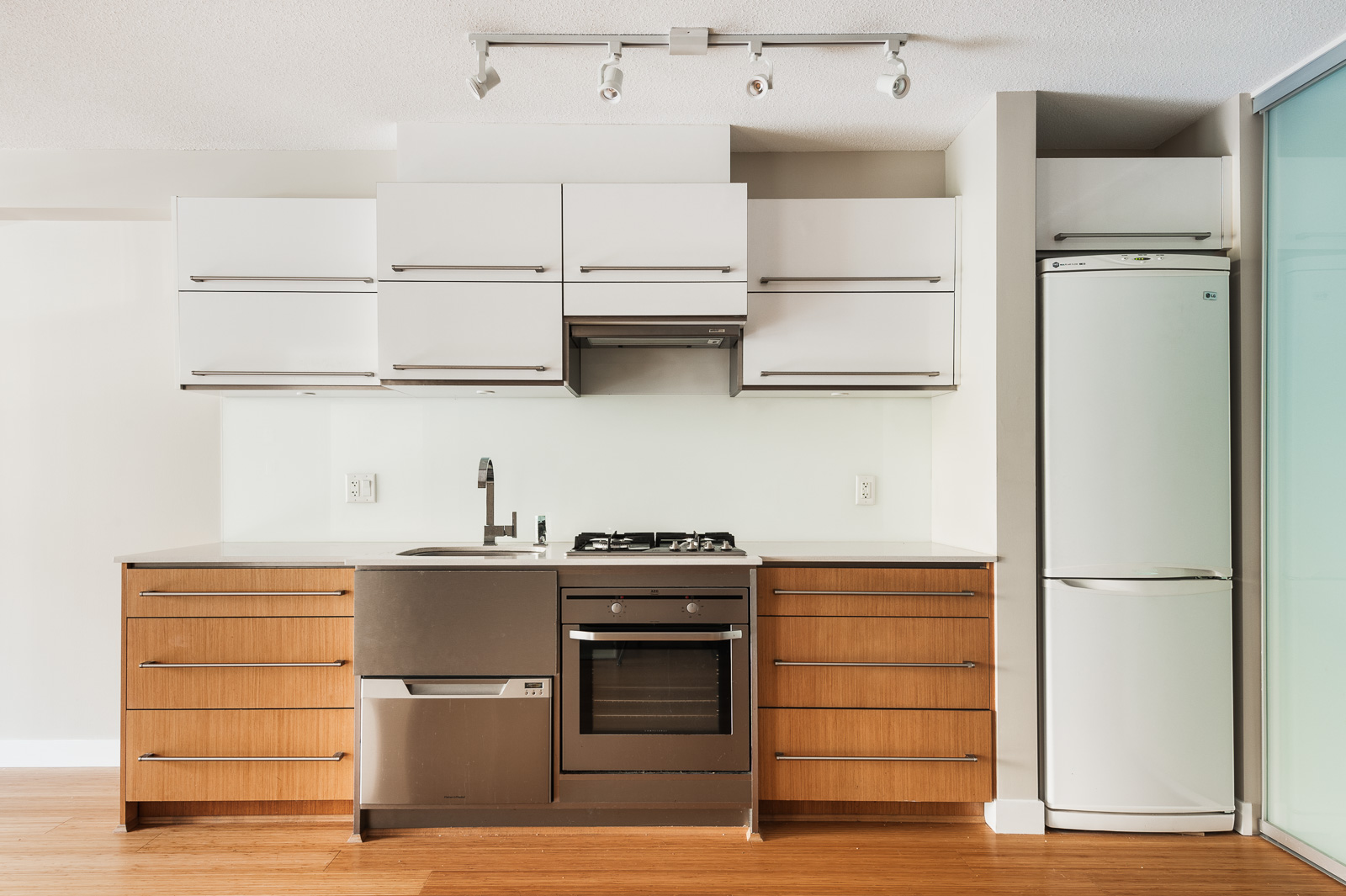 Kitchen with cherry wood and white cabinetry, and stainless steel appliances inside Vancouver rental.