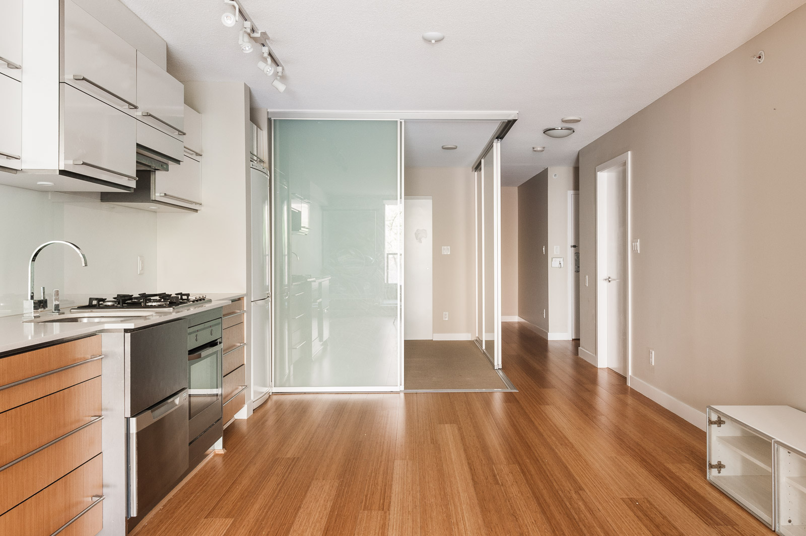 A frosted glass sliding door leads to another bedroom in an unfurnished Vancouver condo rental.