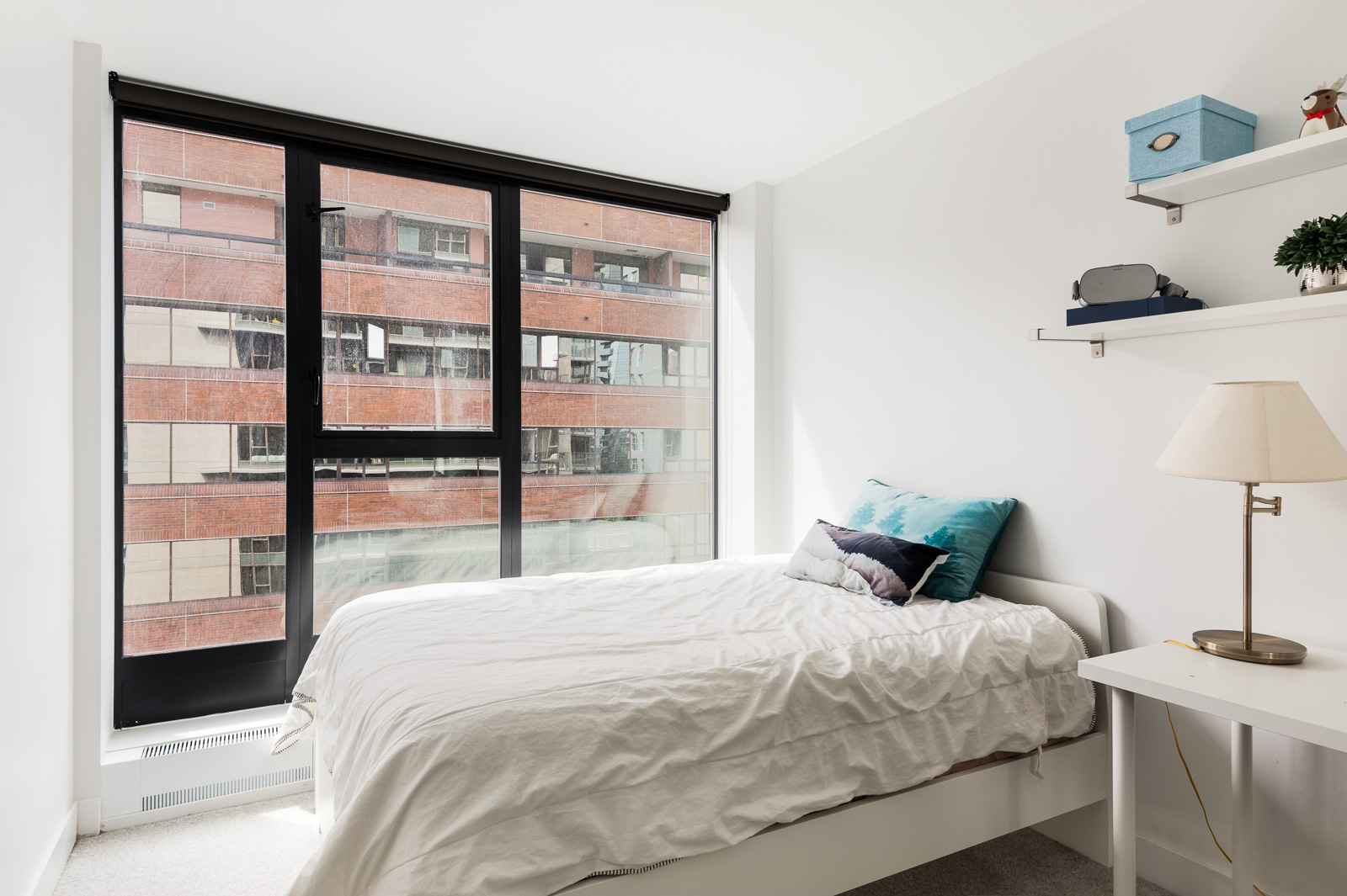 White bedroom with floor-to-ceiling windows offering view from luxury Vancouver condo rental listed by Birds Nest Properties.