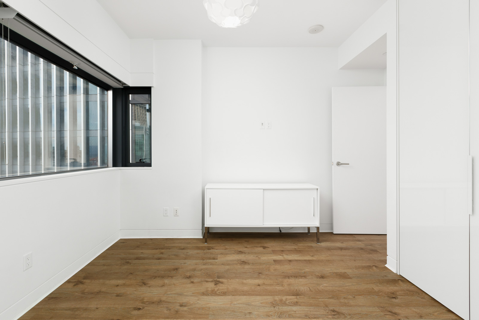 Bedroom with low white dresser stand in Jameson House condo in Downtown Vancouver