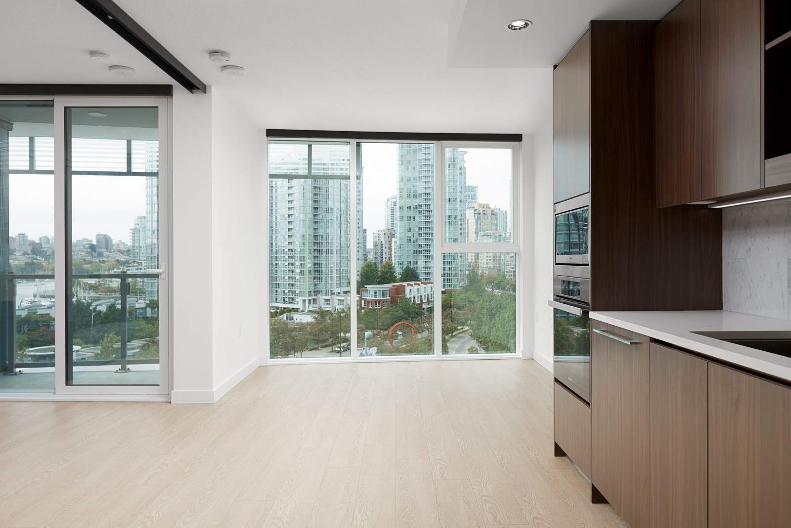 floor to ceiling window in living room of rental condo with kitchen on right