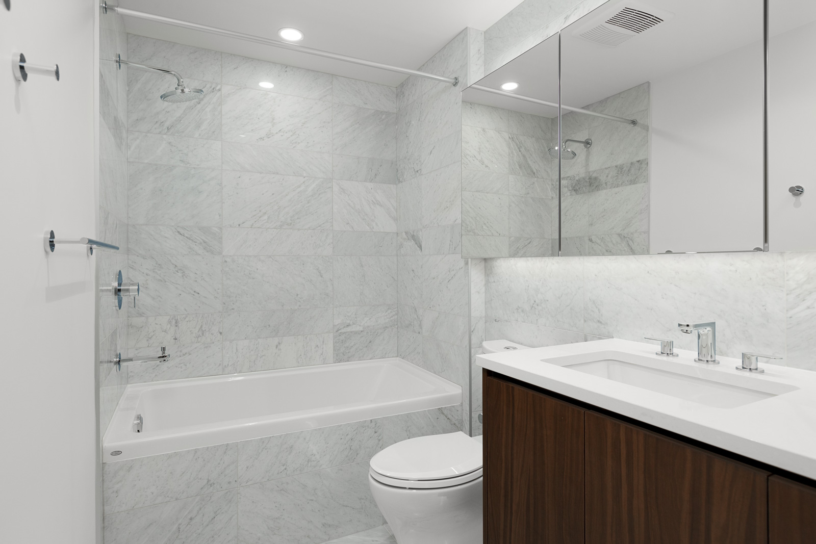 bathroom with marble tiling showing bath tub toilet basin and mirrors