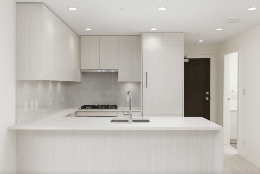 kitchen with white cabinets and entrance door on the right in burnaby condo