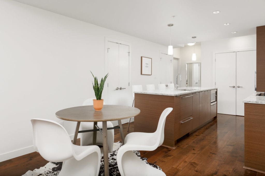small round table in condo living room with kitchen in background
