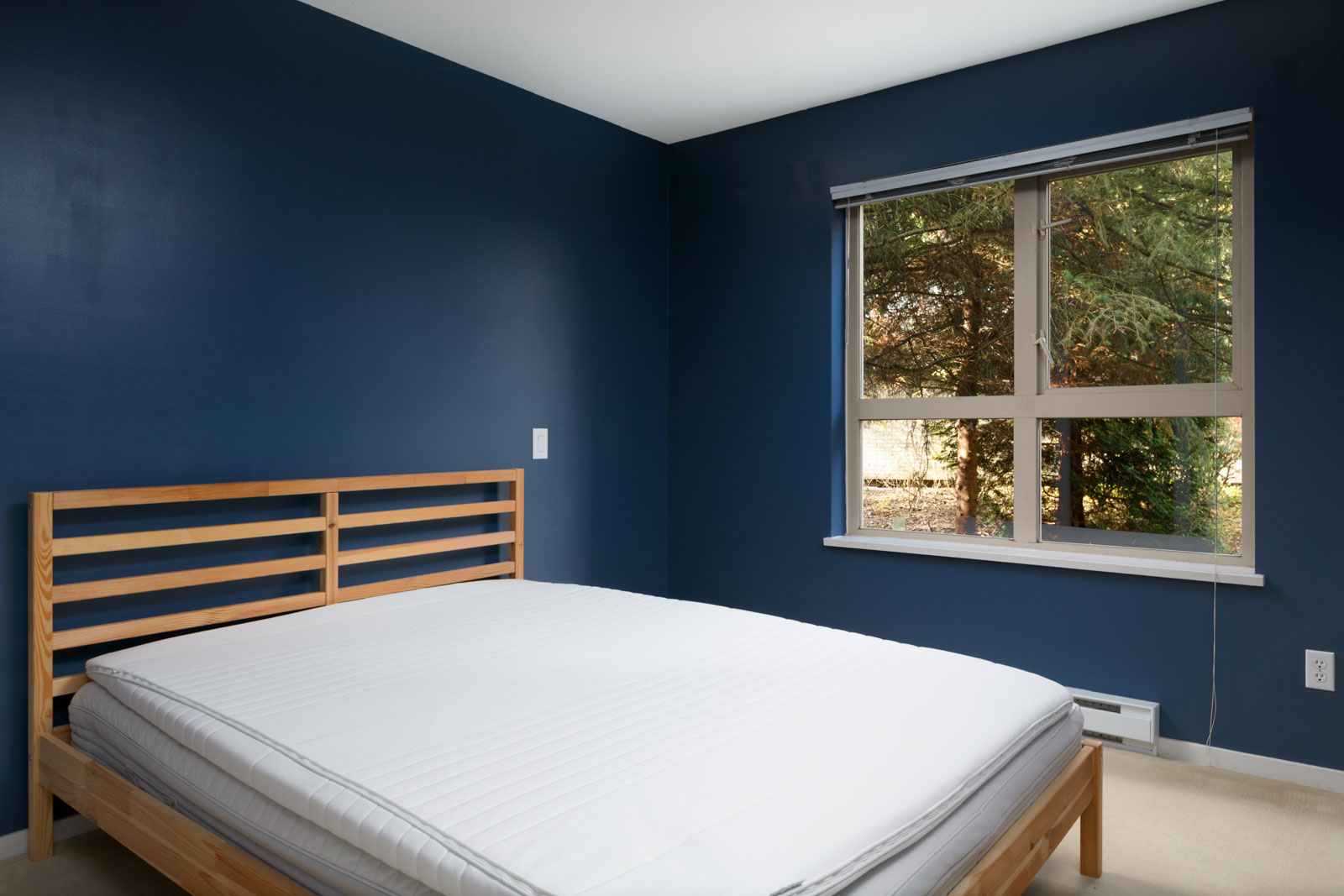bedroom with white bed mattress and blue walls with one window