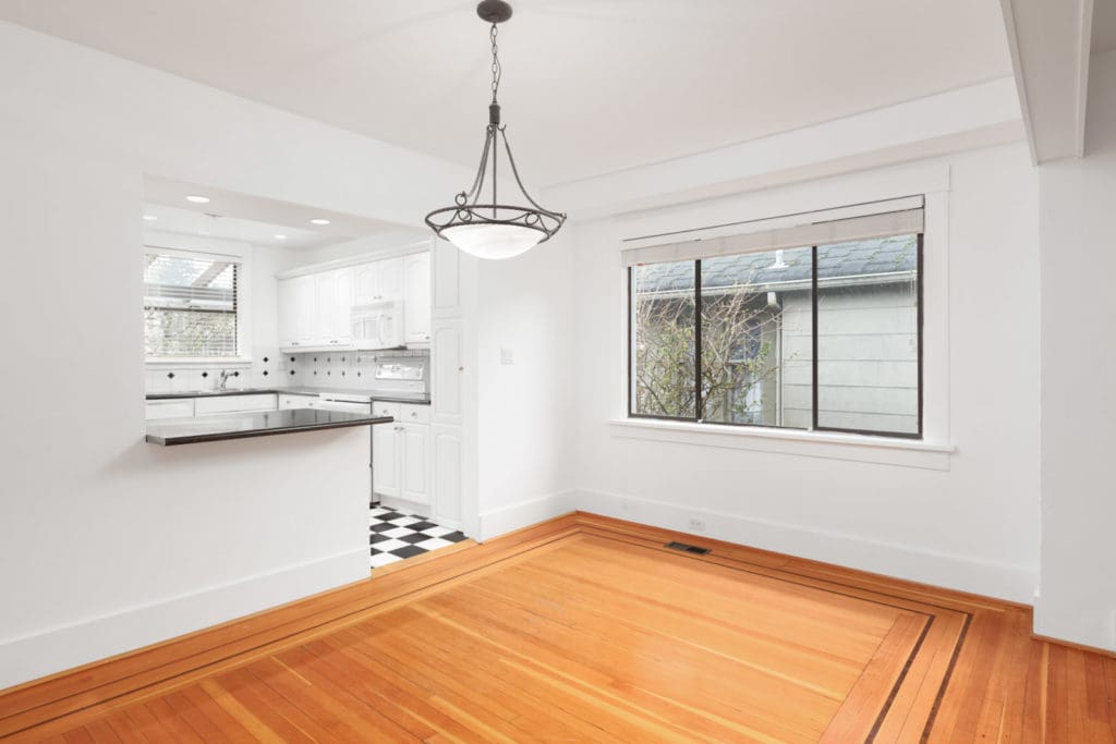 Living room and kitchen in Kerrisdale Vancouver house with hardwood floor and side window facing house next door