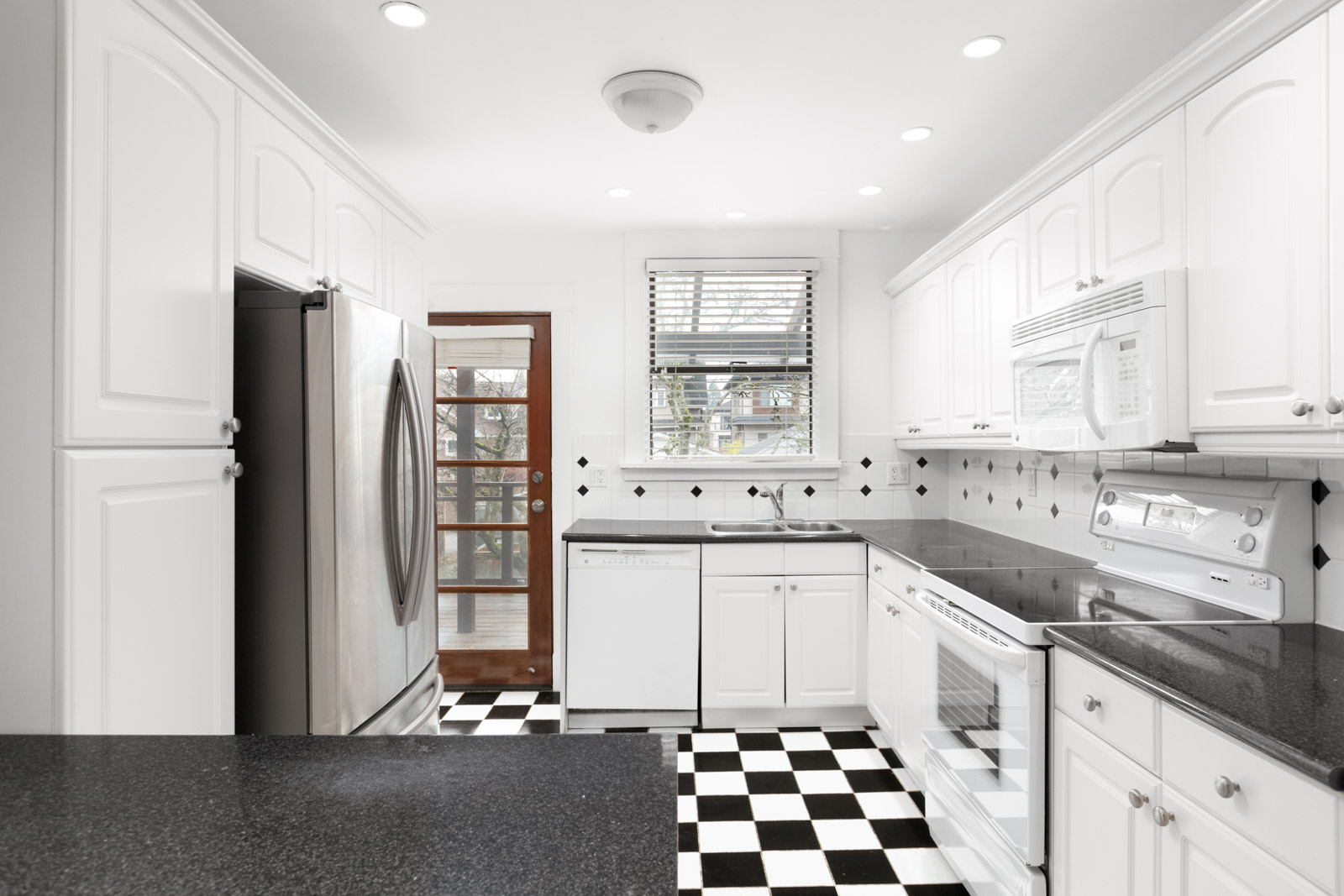 Kitchen with white cabinets and black and white checkered tile floors in Kerrisdale rental house