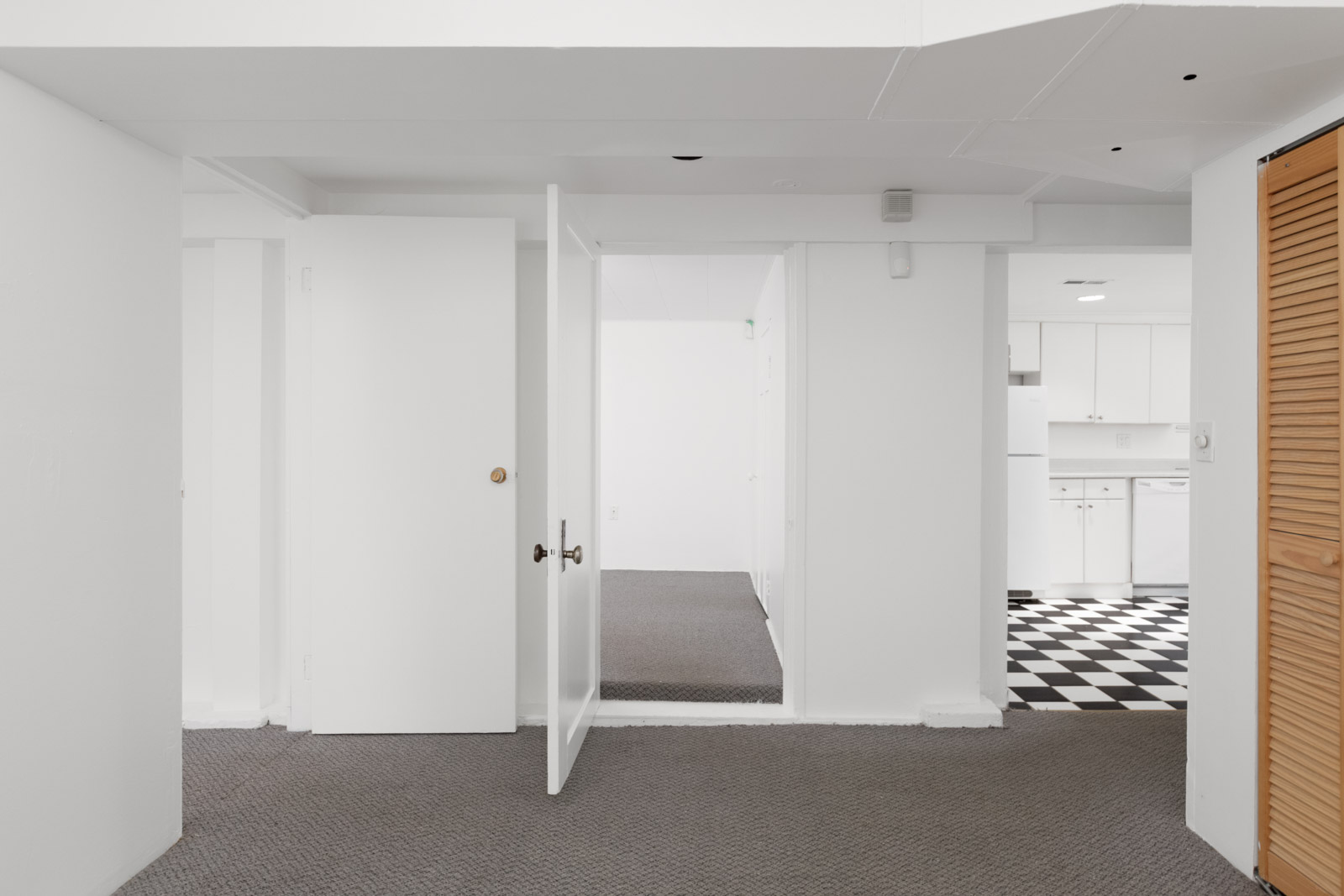 three doors from interior hallway with open middle door and open door to kitchen on the right in kerrisdale house managed by birds nest properties in vancouver