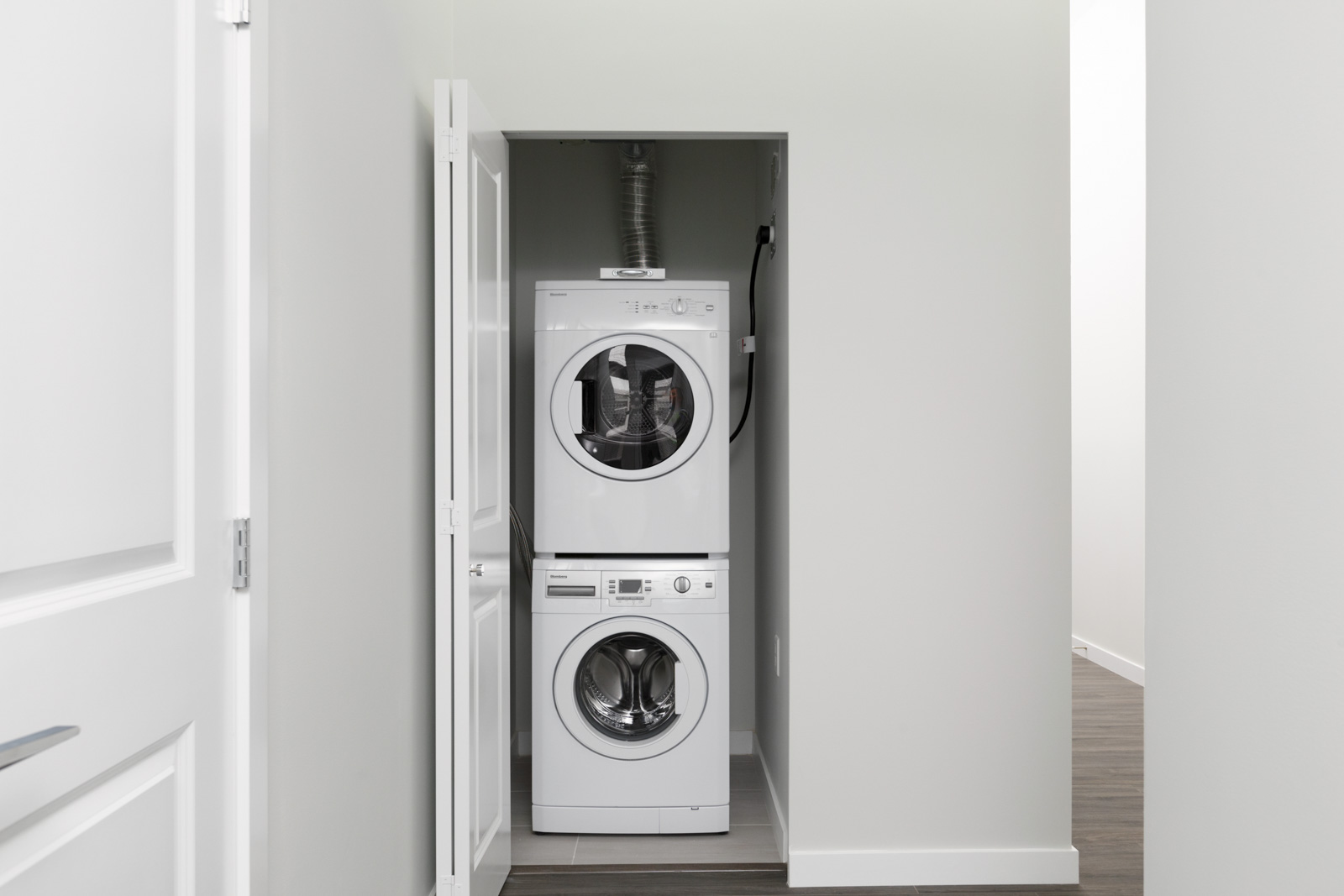 white stacked washer dryer unit with open door along wall