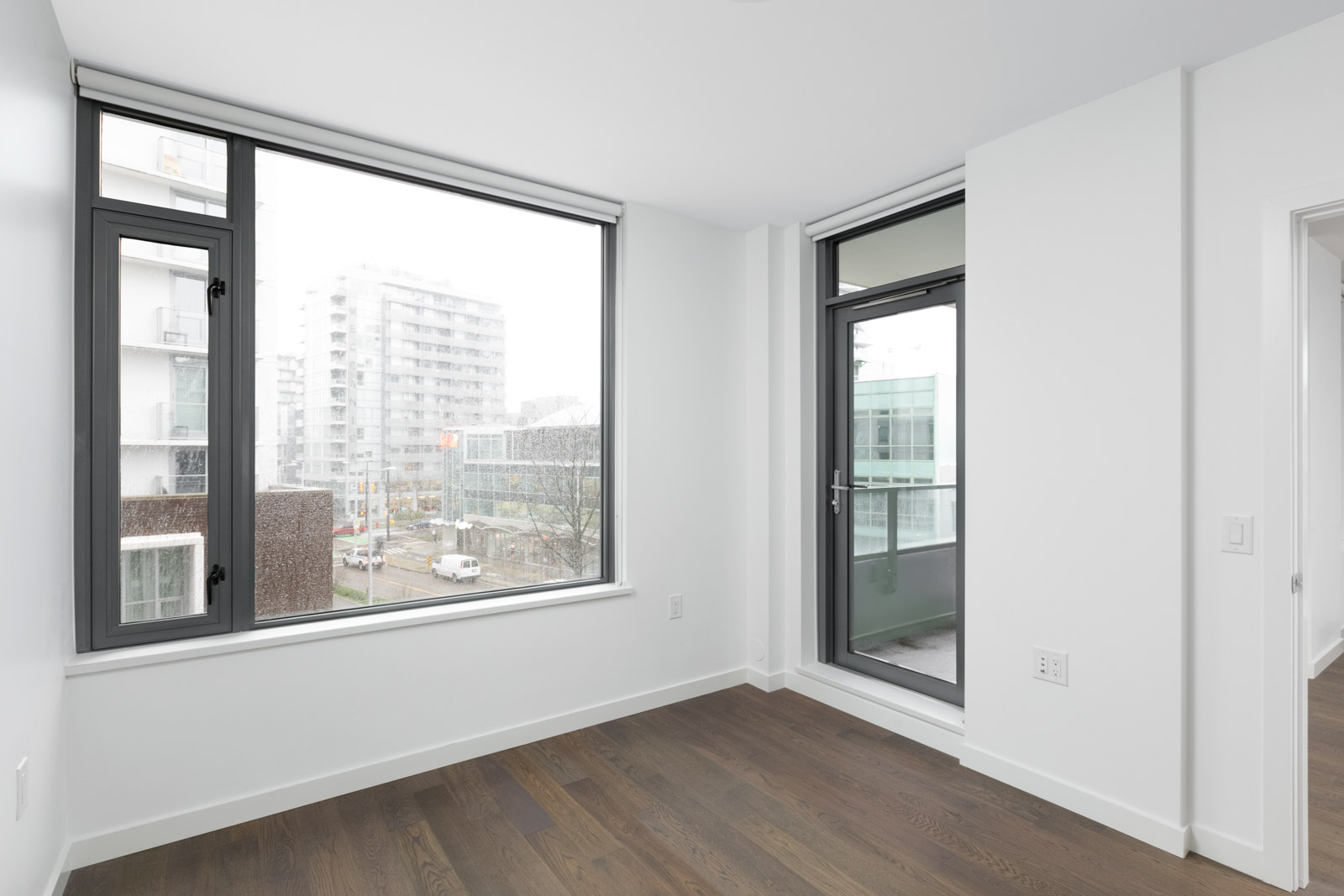 living room with hardwood floors and window looking outside in olympic village vancouver condo rental managed by birds nest properties