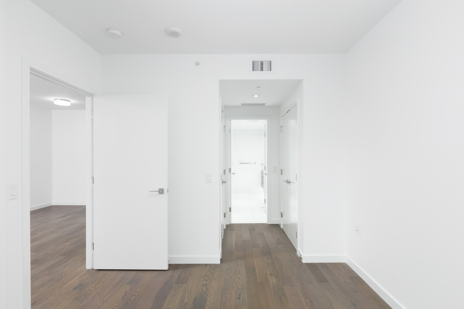 bedroom in leed gold olympic village vancouver condo with hardwood floors and white walls