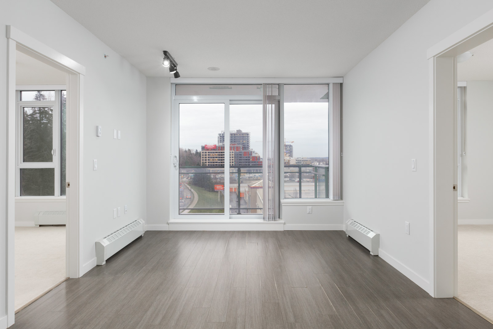condo living room in river district of vancouver with dark hardwood floors and view through floor to ceiling windows of balcony and outside