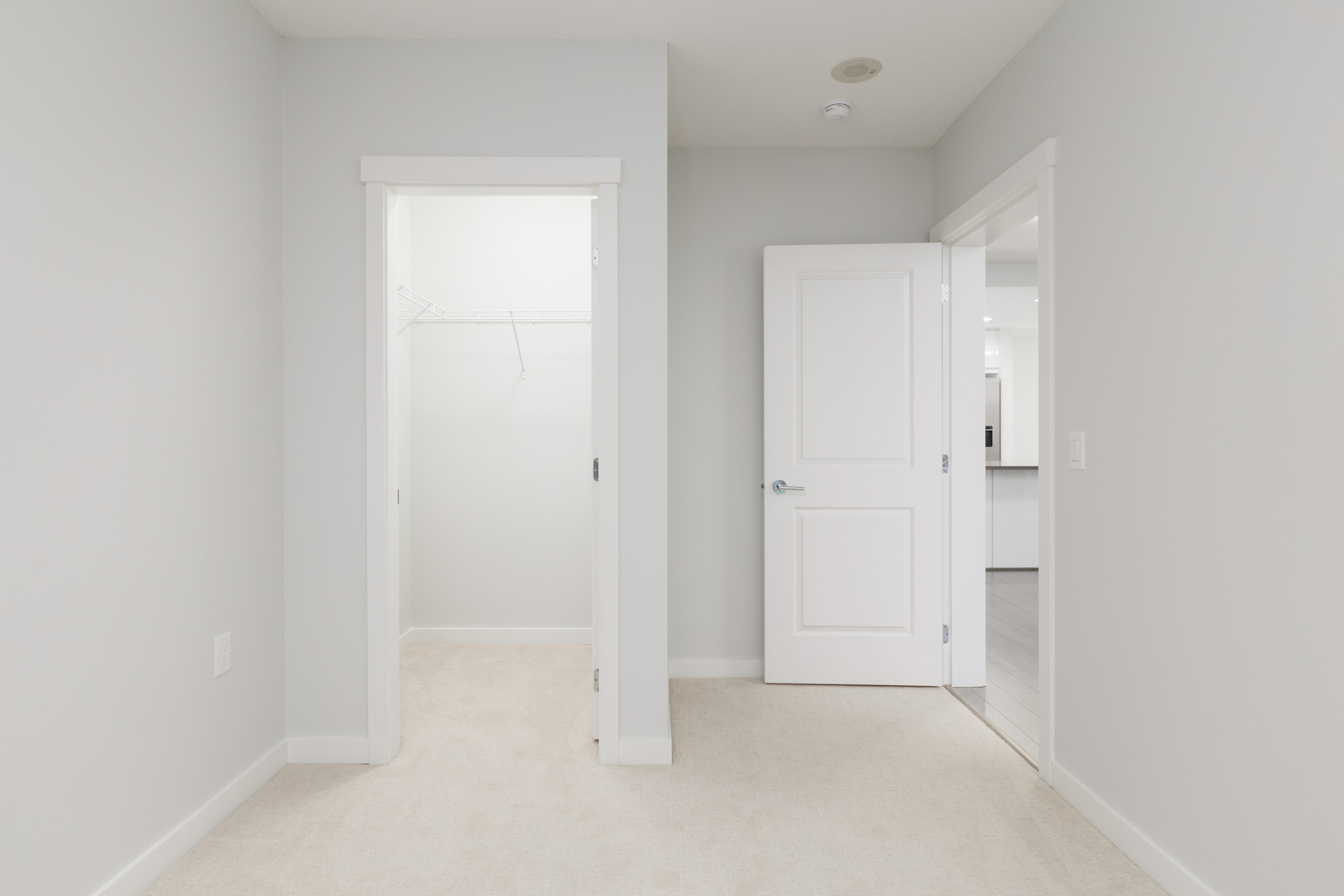 view from bedroom of one door on left to walk in closet and one door on right to bathroom