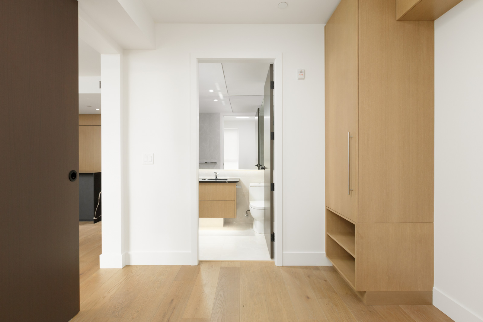 view from bedroom into bathroom in vancouver rental condo at shift little mountain managed by birds nest properties with wardrobe closet on right and partial view into kitchen on left
