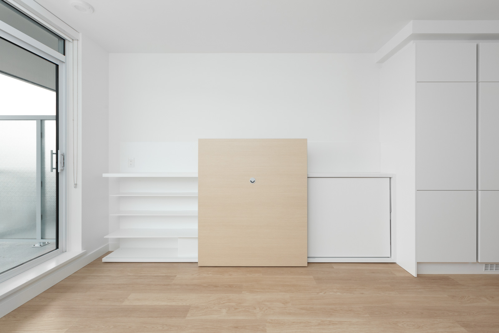 empty condo room with white wall and hardwood floors and cabinet feature