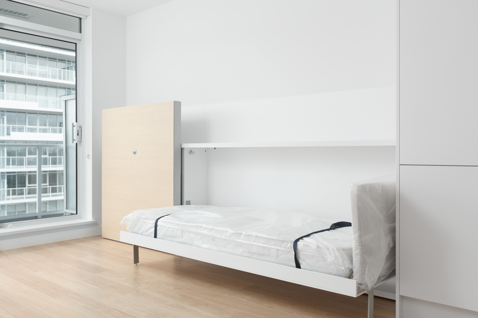 built in bed with white mattress on the right and cabinet feature on left along the wall in empty condo bedroom