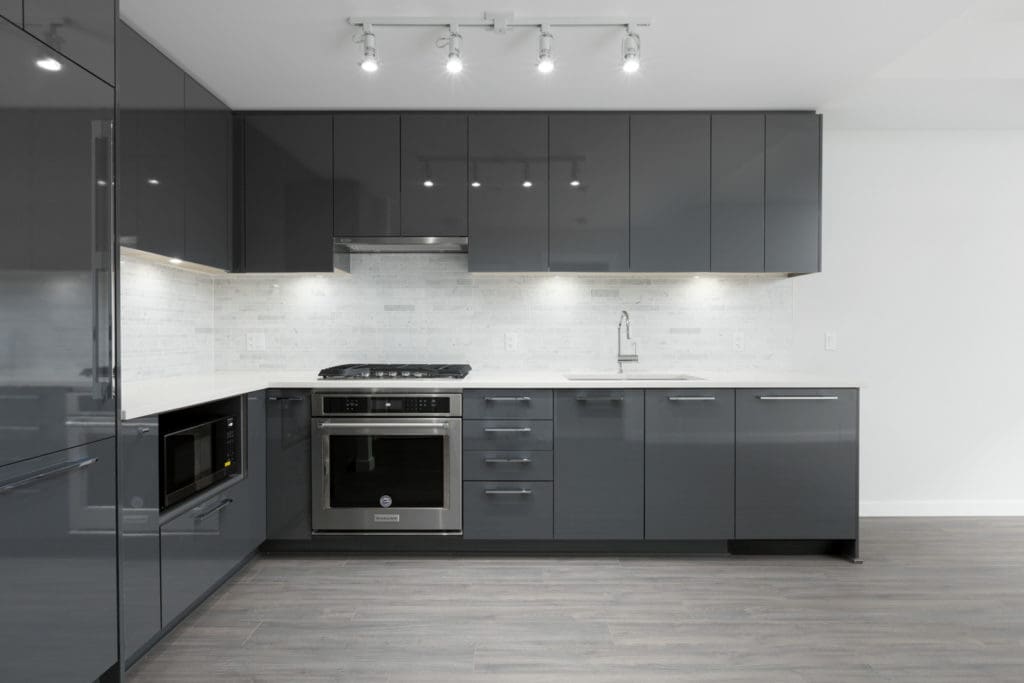 kitchen wall of empty brand new rental condo managed by birds nest properties at trafalgar square in richmond with dark cabinets and stainless steel oven and stovetop