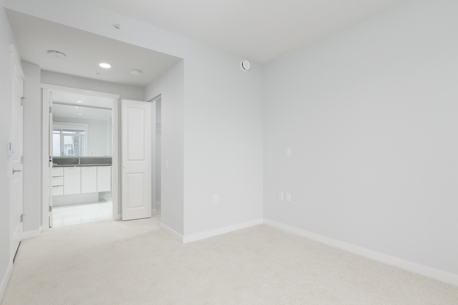 diagonal view of room with open door on left in empty new rental condo at fulton house on madison in brentwood neighbourhood of burnaby