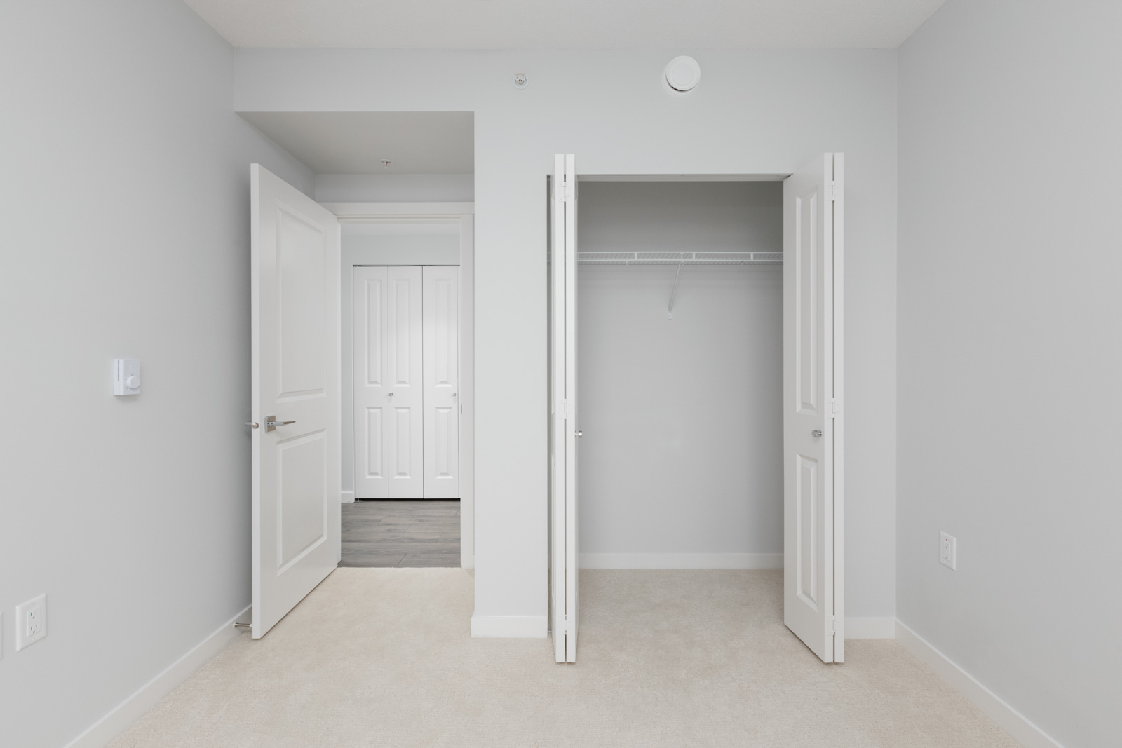 view from bedroom of open closet door on right and open bedroom door to next room in empty new rental condo at fulton house on madison in brentwood neighbourhood of burnaby