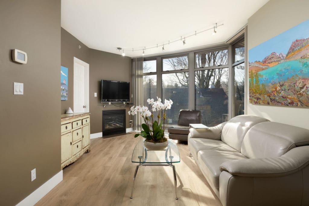 bright living room with track lighting and flowers on glass coffee table in middle in rental condo at crystal court building in south granville vancouver managed by birds nest properties