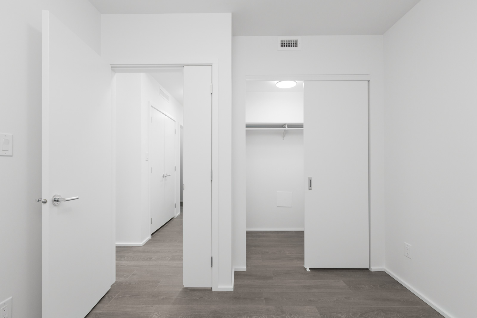 empty bedroom with open closet doors and open door on left and hardwood floors in brentwood tower one condo building