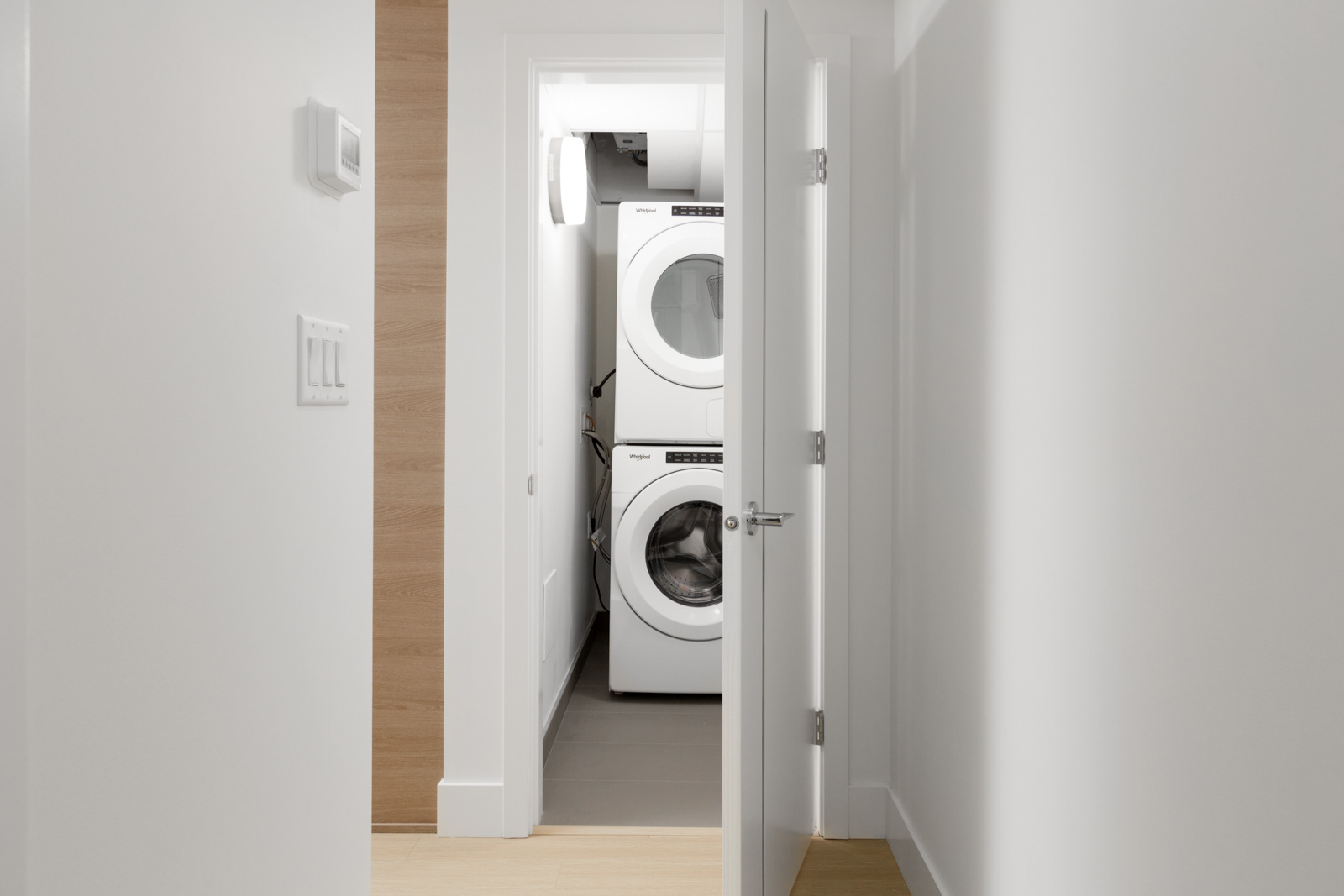stacked white washer and dryer with open closet doors in empty brand new condo managed by birds nest properties at kings crossing in burnaby