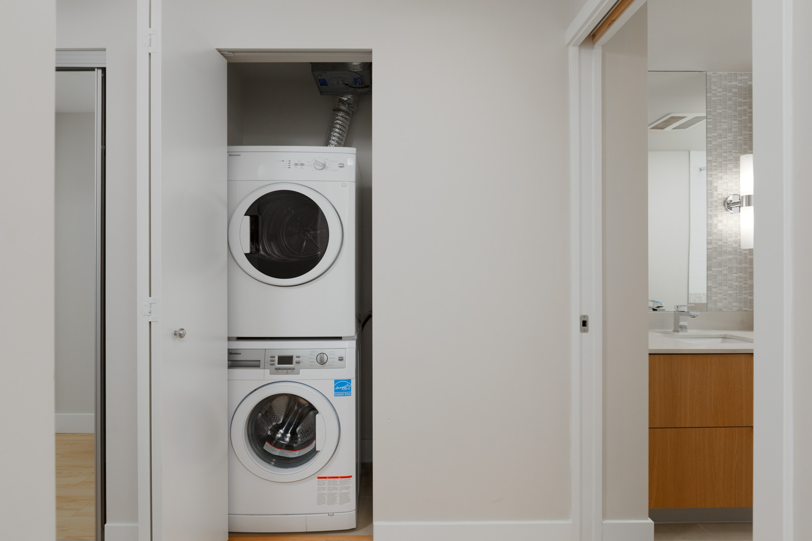 white stacked washer dryer in laundry closet of rental condo at tower green in false creek olympic village vancouver managed by birds nest properties