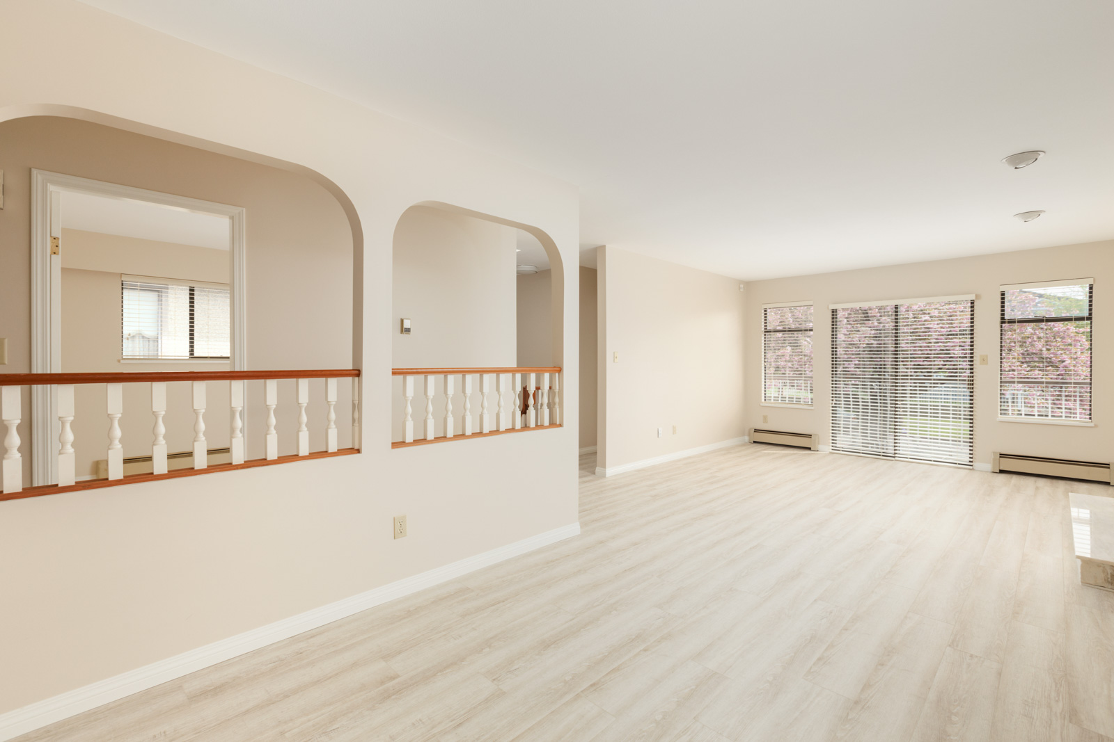 Spacious living area with natural sunlight from wall-to-wall windows in a room with a staircase leading to the ground floor with laminate hardwood flooring in a rental home in East Vancouver provided by Birds Nest Properties