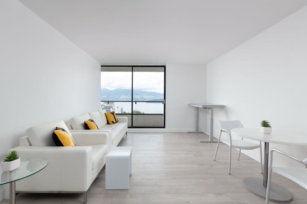 living room of rental property with sofa on left and window looking out over kitsilano beach of vancouver
