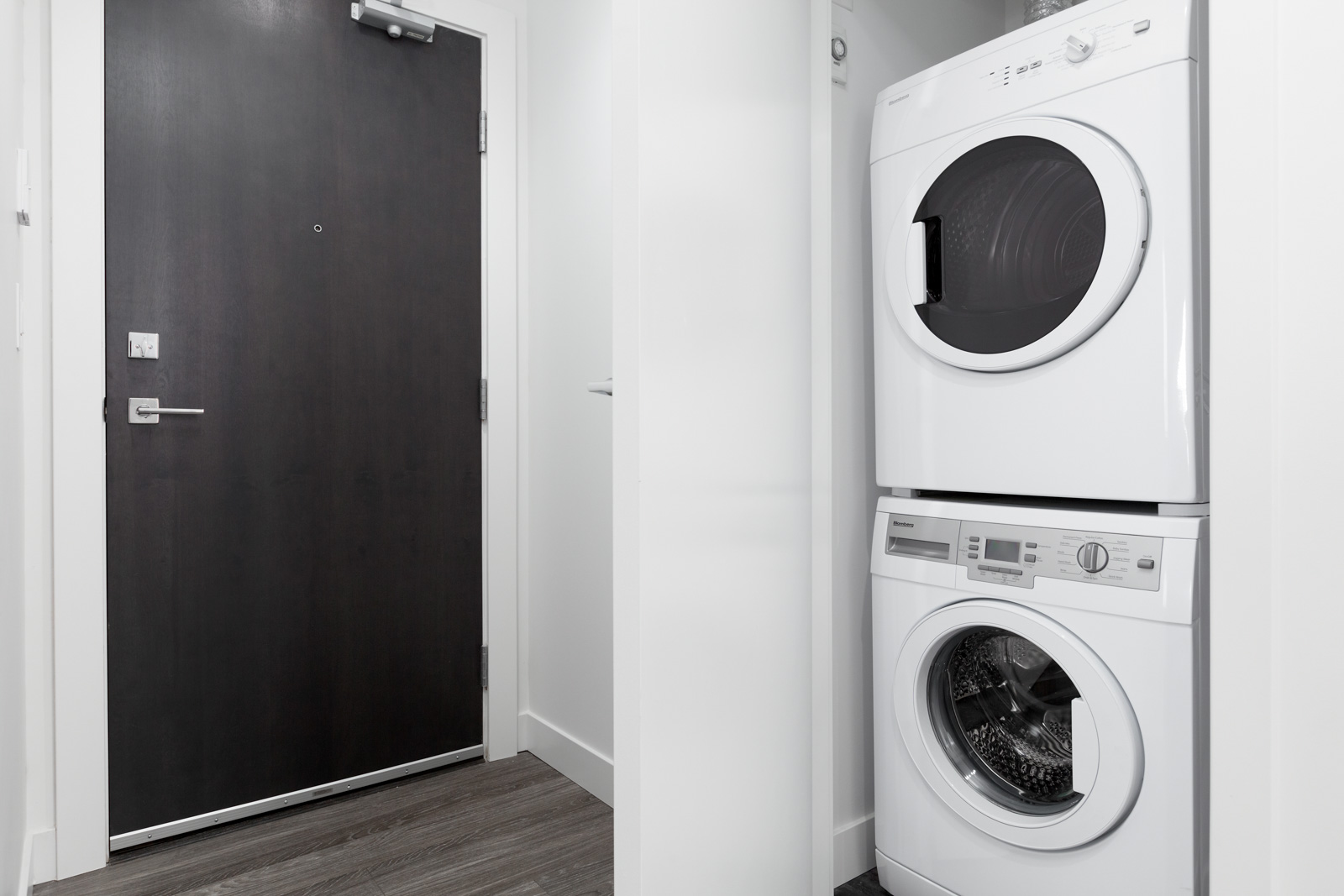 dark entry door on left and washer dryer on right of rental condo in the Yaletown neighbourhood of Vancouver