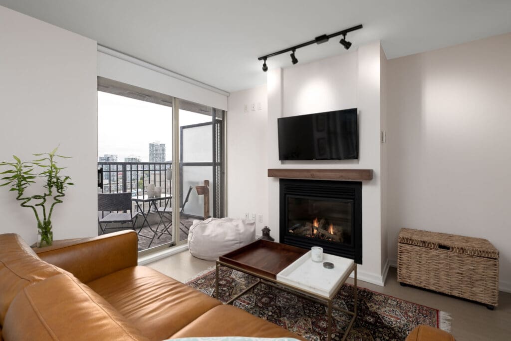 living room with balcony of rental condo fully furnished with tv fireplace and couch at mondrian 2 building in yaletown neighbourhood of downtown vancouver
