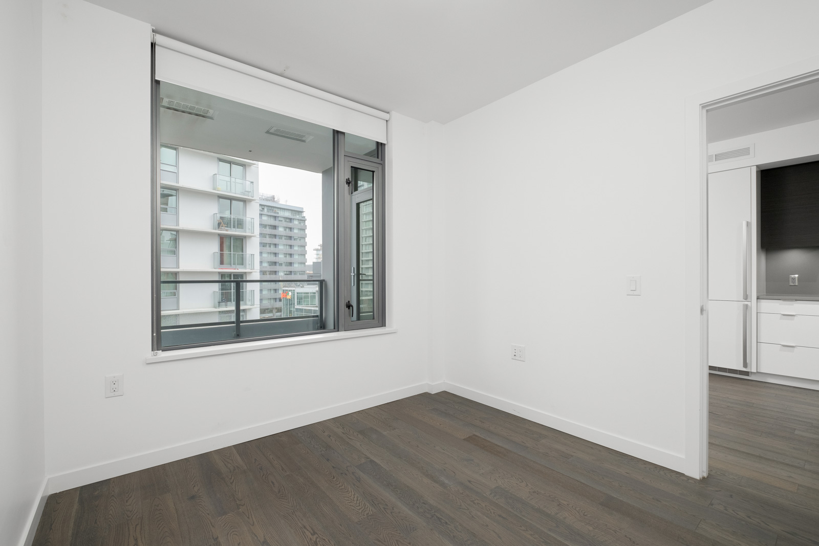 bedroom corner with hardwood floors and white walls and window on the left in false creek vancouver