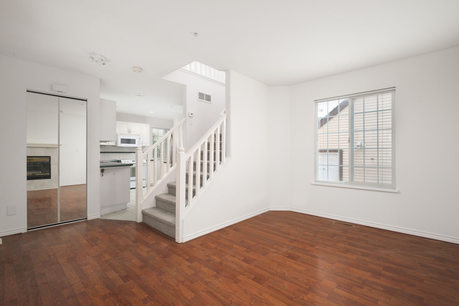 living room with stairs and view of kitchen on left in rental house in east vancouver
