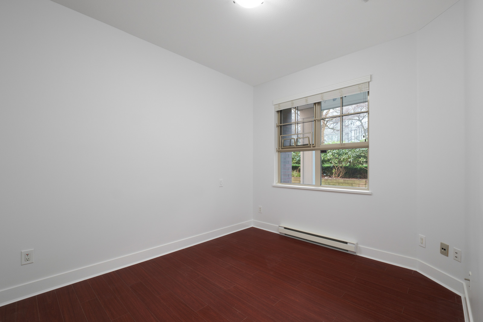 bedroom with hardwood flooring and white walls and window on right in rental apartment in alexandra house in shaughnessy of vancouver westside