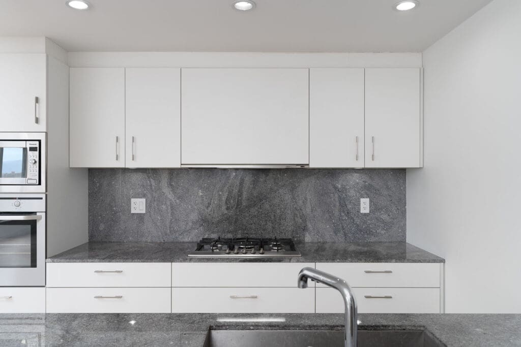 kitchen with white cabinets and granite countertops in grey shades