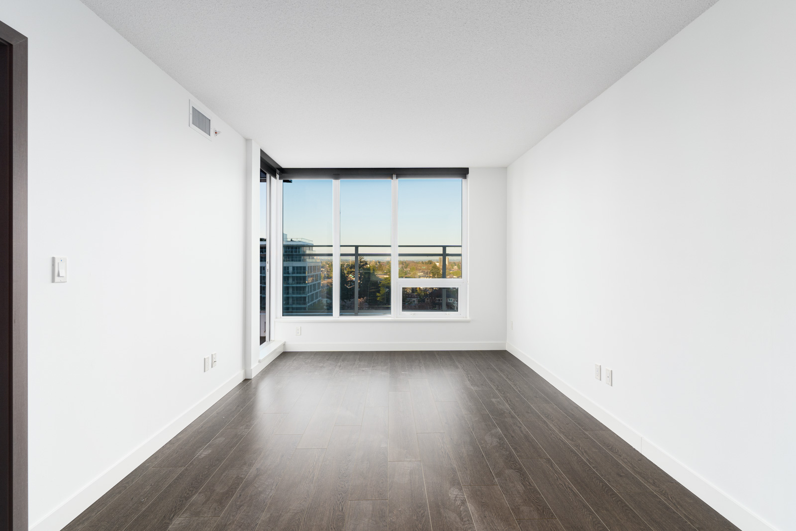 bright living room with laminate floors, white walls and floor to ceiling windows