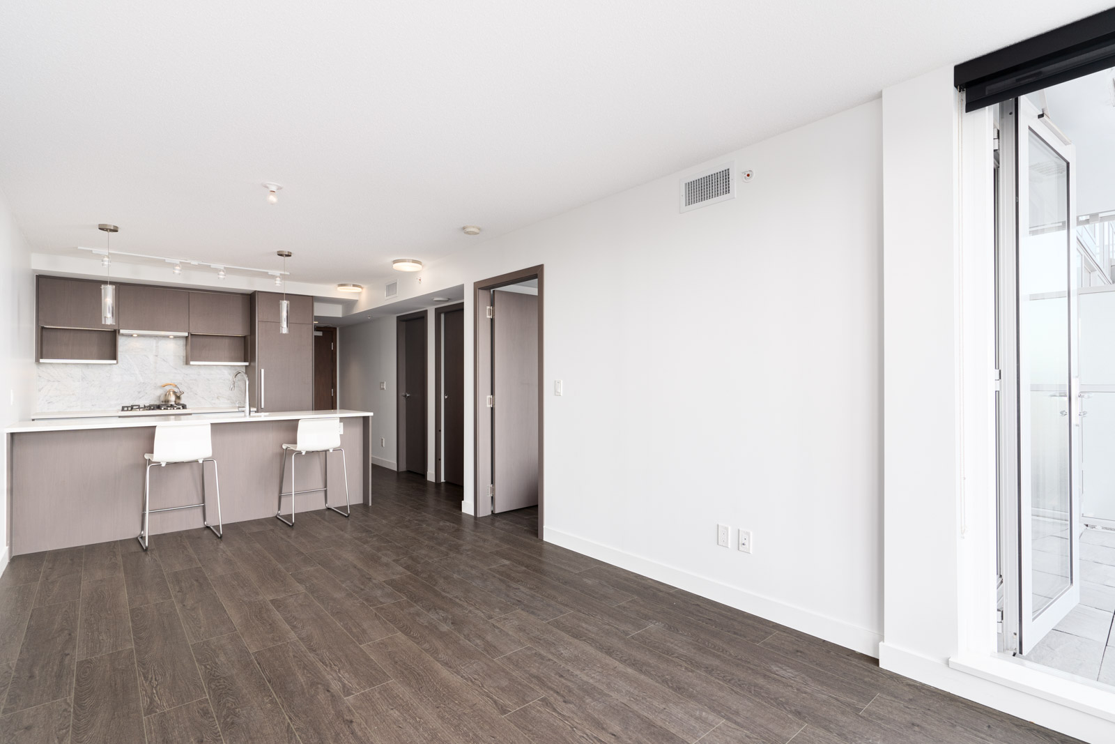 living room and kitchen area with laminate floors and white walls in a rental condo in richmond by birds nest properties