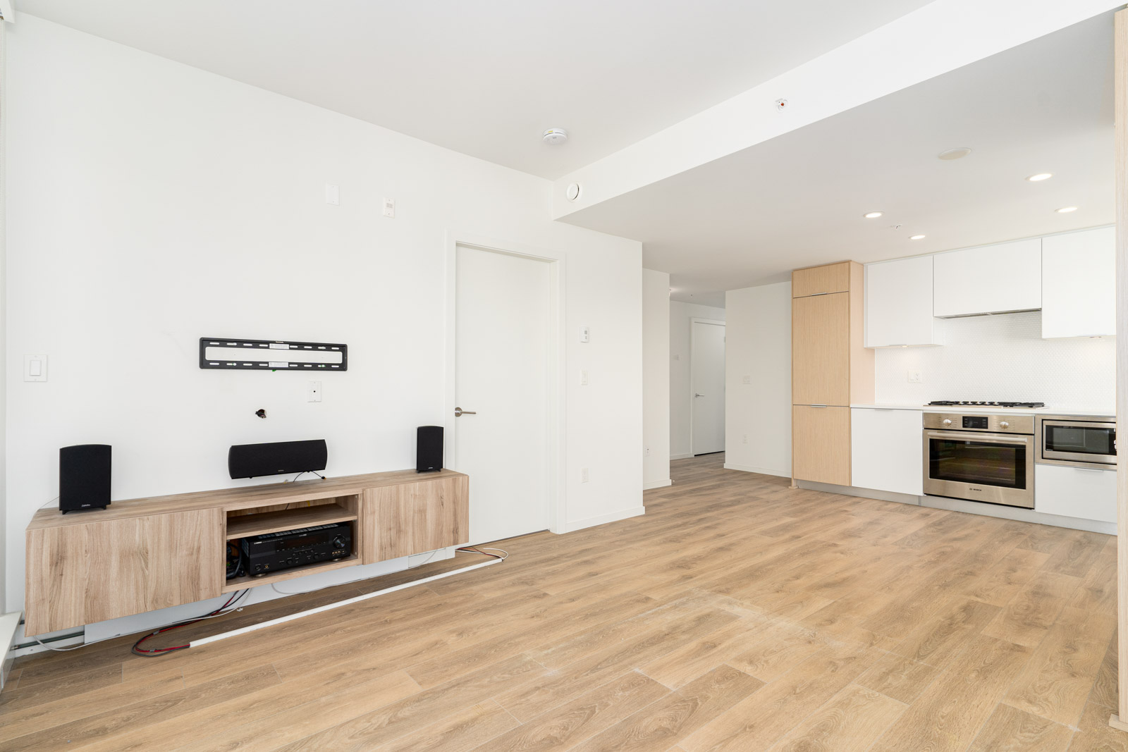 Living room area with open kitchen showing entry to hallway and bedrooms